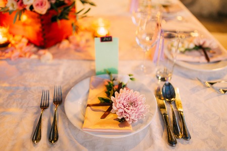 Table setting at a wedding banquet. Decoration flowers. A close-up of a plate with cutlery.