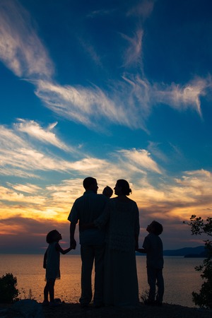 Silhouette of a family with children against the backdrop of the setting sun and sea in Montenegro.の写真素材