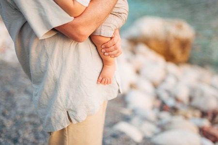 Childrens legs and feet of parents. The family walks along the beach in Montenegro.