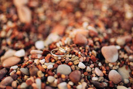 Wedding rings of newlyweds on beach pebbles. Engagement gold rings. Wedding in Montenegro.の写真素材