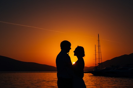 Silhouette of a newlywed couple on the background of the setting sun on the sea in Montenegro.の写真素材