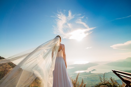 Happy beautiful bride outdoors. Wedding dress fluttering in the wind. Building in the background.の写真素材