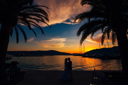 Silhouette of a newlywed couple on the background of the setting sun on the sea in Montenegro.