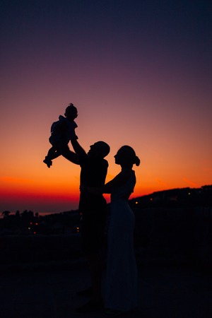 Silhouette of a family with children against the backdrop of the setting sun and sea in Montenegro.の写真素材