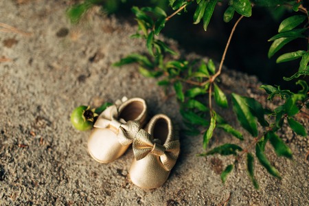 Baby booties and a pomegranate fruit on a stone background.の写真素材