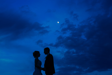 Silhouette of the newlyweds against the sky at sunset. Wedding in Montenegro. Silhouette of a couple. Silhouette of the bride and groom.の写真素材