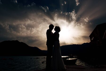 Silhouette of a newlywed couple at the sea at sunset. Wedding in Montenegro. Silhouettes of the couple, the bride and groom.の写真素材