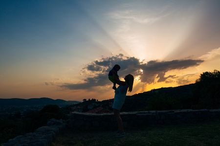 Silhouette of mother with baby at sunset. Montenegro, Sveti Stefan.の写真素材