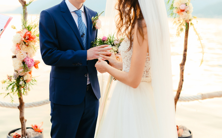 The bride puts the ring on the bridegroom at the wedding ceremony. Wedding in Montenegro.の写真素材
