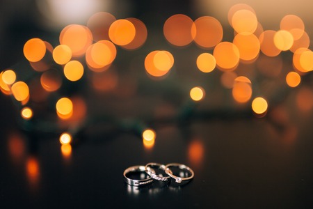 Wedding rings on a yellow background bokeh of garlands. Magical beautiful background.の写真素材