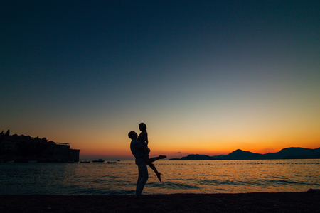 Silhouettes of couples near Sveti Stefan island in Montenegroの写真素材
