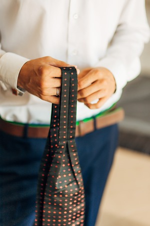 Male hands tie a bow tie. Wedding in Montenegro. Wedding accessories of the groom.の写真素材