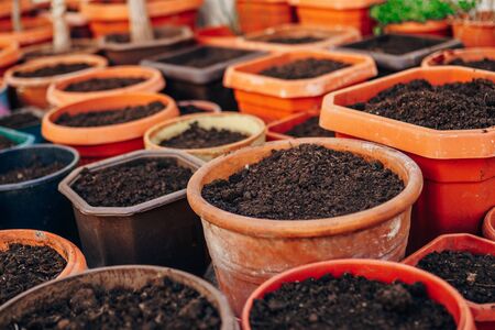 A lot of pots with earth. Brown flower pots with earth, stand next to each otherの写真素材
