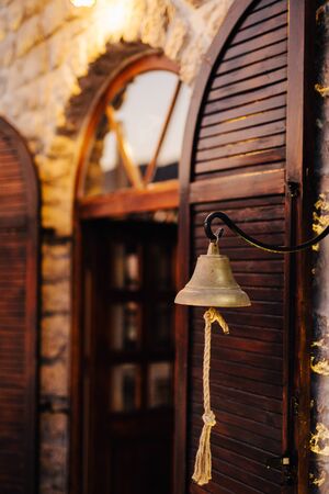 Metal ship bell against the background of an old wooden window with shuttersの写真素材