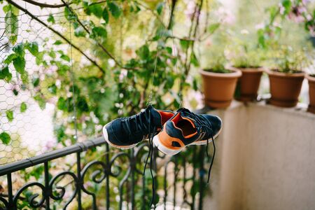 Washing and Drying sneakers. The crumbs are dry on the balcony. Drying shoes in a natural way. A pair of blue-orange crowns.の写真素材