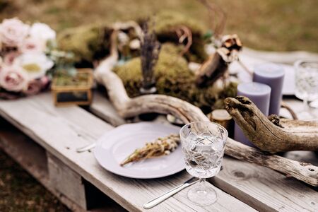 Close-up of a wedding dinner table. A table made of construction pallet decorated with driftwood and a car. The branches of the tree lie among plates and glasses. Wedding in Icelandの写真素材