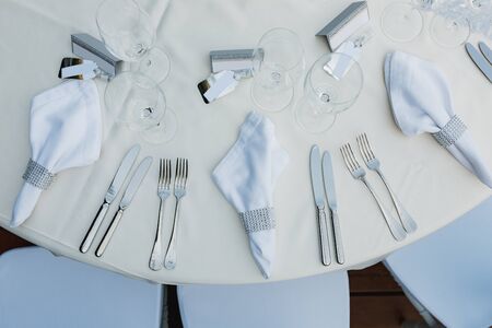 Close-up of a wedding dinner table. The cutlery is on the table - knives, forks, napkins with a ring...