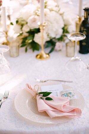 Wedding dinner table reception. Stone table with pink runner, plates with pattern and rag pink napkins, candles with led-light bulbs in the rays of sunset. Top viewの写真素材