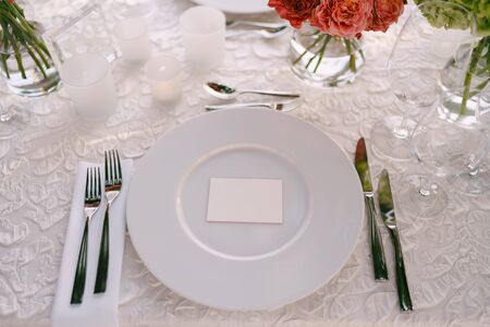 Wedding dinner table reception. View from above on white round plates close-up. Bouquets of pink,...