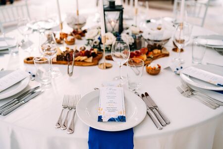 Wedding dinner table reception. White plate on the table, three forks on left, three knives on the right. The wedding menu is in the plate. Top viewの写真素材