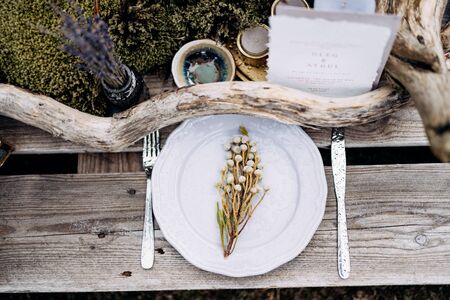 An impromptu table for two of the construction pallet on grey grass in Iceland. Light purple plate, snags, moss, purple candles, lavender, bouquet of flowers.の写真素材