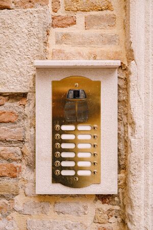Close-ups of building facades in Venice, Italy. An old vintage intercom and a mailbox on stone wall. On door where placed this old rusty doorbells.の写真素材
