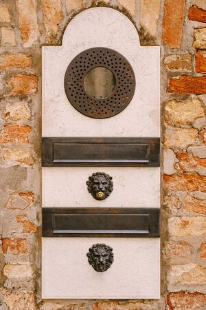Close-ups of building facades in Venice, Italy. An old vintage intercom and a mailbox on stone wall. On door where placed this old rusty doorbells.の写真素材
