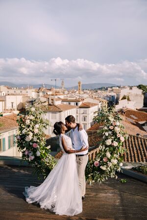 Interracial wedding couple. Destination fine-art wedding in Florence, Italy. A wedding ceremony on the roof of the building, with cityscape views of the city and the Cathedral of Santa Maria Del Fioreの写真素材