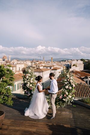 Mixed-race wedding couple. Destination fine-art wedding in Florence, Italy. A wedding ceremony on the roof of the building, with cityscape views of the city and the Cathedral of Santa Maria Del Fioreの写真素材