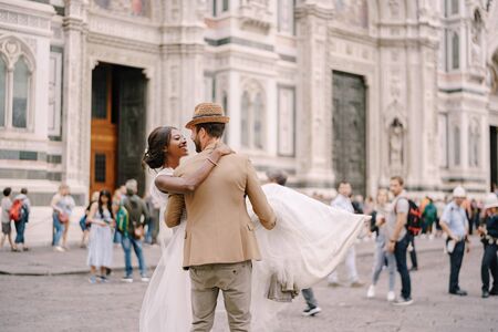 Interracial wedding couple. Wedding in Florence, Italy. Caucasian groom circles and kisses African-American bride in Piazza del Duomo.の写真素材