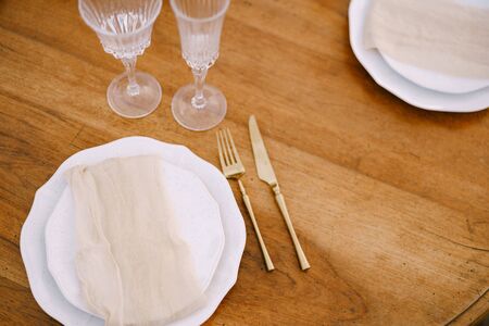 White plates on a wooden table, table setting for a wedding dinner.