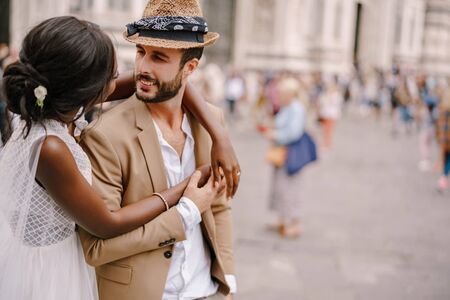 Interracial wedding couple. Wedding in Florence, Italy. African-American bride hugs from behind a Caucasian groom.の写真素材