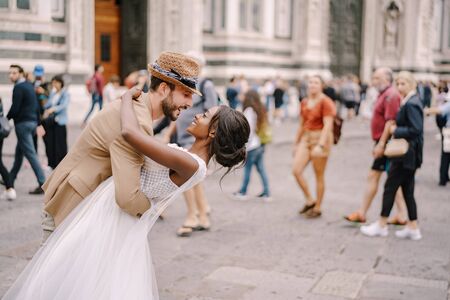 African-American bride and Caucasian groom cuddling in Piazza del Duomo. Wedding in Florence, Italy. Interracial wedding coupleの写真素材