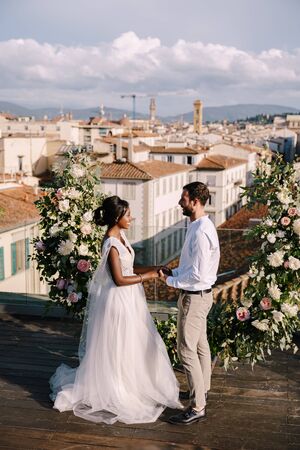 Destination fine-art wedding in Florence, Italy. A wedding ceremony on the roof of the building, with cityscape views of the city and the Cathedral of Santa Maria Del Fiore. Multiracial wedding coupleの写真素材