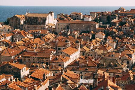 Roofs of the old city of Dubrovnik, orange roof tiles on houses, a view from a height, from the wall. Domes of The Church of the Holy Annunciation and St. Ignatius Church.の写真素材