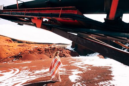 Portrait of a bride model in a golden wedding evening dress, in a yellow-red sandy quarry, in the crater of a volcano in Iceland, Golden Circle. The bride walks near the career vibrating screen.の写真素材