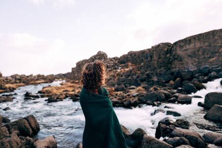 A girl in a red dress near Ehsaraurfoss Falls, Ehsarau River, National Park, Tingwedlir, Sudurland...