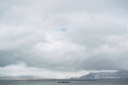 The barge sails on the Atlantic Ocean, near Iceland, against the backdrop of snow-capped mountains....