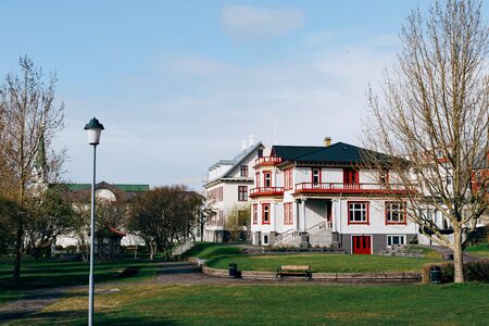 Beautiful white two-story house with a black roof, near the park in Reykjavik, the capital of...