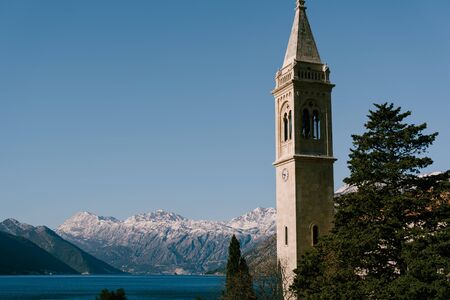 Church of St. Eustachius tower tower against Kotor Bay and snow-capped mountains in Montenegro.