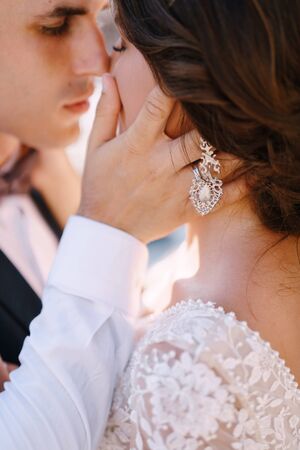 Close-up, the wedding couple is almost kissing. The groom strokes the brides hand on the cheek. Fine-art wedding photo in Montenegro, Perast.の写真素材