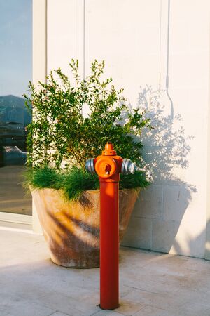 Red high fire hydrant on the street.
