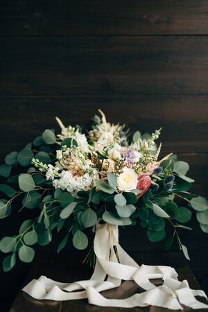 bridal bouquet of white and cream roses, branches of eucalyptus tree, protea, eryngium, delphinium and white ribbonsの写真素材