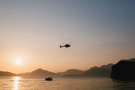 Passenger helicopter flies in the sky, over the sea and mountains in Montenegro. High quality photo