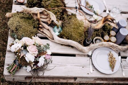 bridal bouquet of white roses, brunia and leucadendron , bouquet of dried lavender on the romantic outing with table decoration, candles, dried branches and moss in Iceland. High quality photoの写真素材