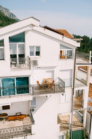 Cozy balconies with wooden garden furniture on the facade of the white building.の写真素材