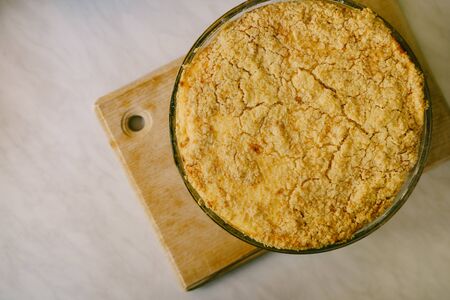 Hungarian-style crumble pie with cheesecake feeling in a glass fire-resistant bowl on a wooden boardの写真素材