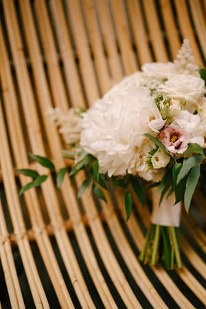bridal bouquet of white peonies, roses, pink eustoma, astilbe and branches of eucalypt tree on a straw chair. High quality photoの写真素材