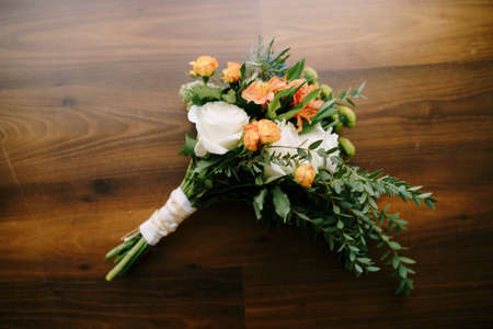 bridal bouquet of white and orange roses, eringyum, ammi, boxwood branches, alstroemeria with white ribbons on the floor. High quality photoの写真素材