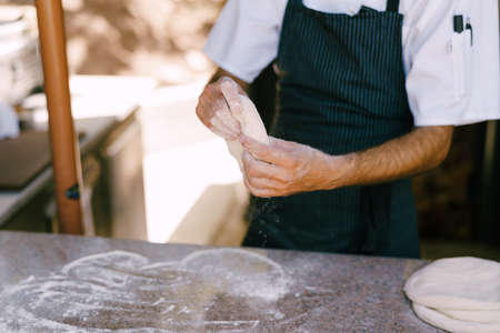 Chef's hands close-up. Prepares the dough for pizza, rolls out in round shapes with his hands. High quality photoの写真素材